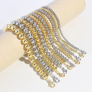 Golden and silver beaded bracelets with lobster clasps on a cylinder display stand