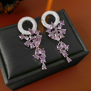 Dettaglio macro di orecchini in argento con gemme a goccia viola e zirconi