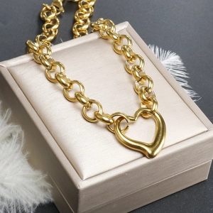 Macro view of polished gold hollow heart pendant on coarse chunky link chain