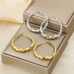Close-up of gold and silver twisted C-shape hoop earrings on a jewelry box with silk