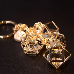 Golden keychain with crystal cubes and metal ring on black leather texture background