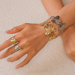 Detail of gold and silver floral metal bangles with brushed texture and open cuff design