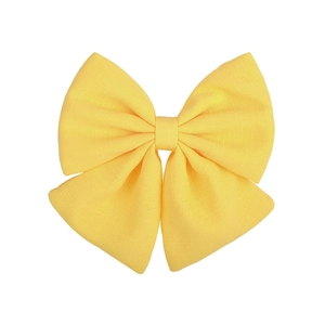 Detail shot of a yellow satin fabric bow hair clip with polished metal duckbill clip