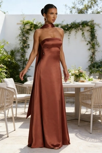 Detail of copper satin backless evening gown with neck ribbon in a luxury garden