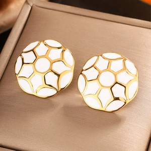 Close-up of circular 18K gold plated earrings with white enamel honeycomb patterns
