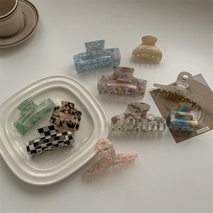 Detailed overhead view of premium acetate hair claws in various marble and plaid patterns