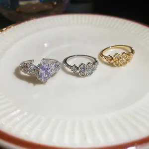 Elegant zircon flower open rings in silver and gold finish on a white textured ceramic plate