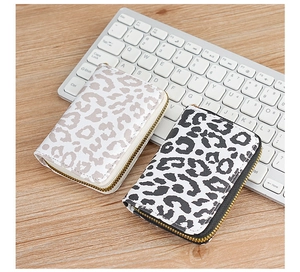 Detail view of leopard print card holders with gold zippers on a laptop keyboard