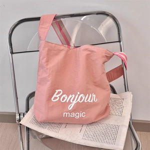 Dettaglio borsa in tela rosa con tracolla a righe e scritta stampata Bonjour magic