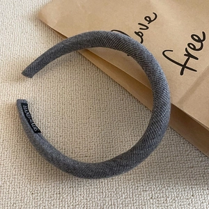 Detailed close-up of grey ribbed knit headband featuring a small Hand Made label