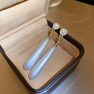 Detail of elegant pearl drop earrings with frosted pendants in a velvet jewelry box