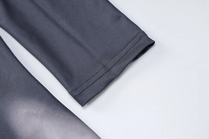 Detail of grey gradient bodysuit showing neat double-stitch sewing and knit fabric texture
