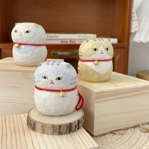 Detail view of three hand-carved wooden fat cat figurines with red bell collars