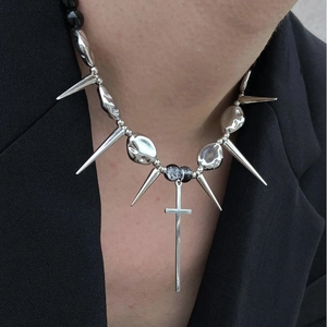 Punk silver cross pendant necklace with metallic spikes and black beads on black suit