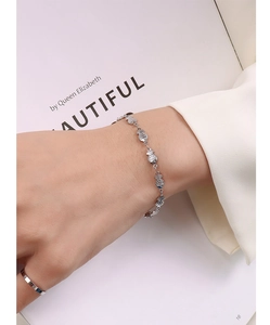 Detailed close-up of minimalist silver fish tail bracelet and simple polished ring