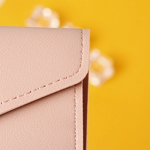 Macro shot of pink leather texture and neat stitching on a minimalist long wallet for women