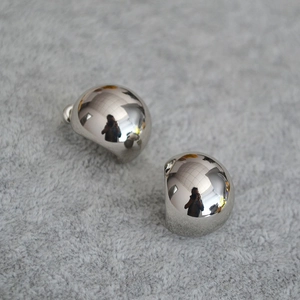 Close-up of silver-tone hemispherical stud earrings on soft grey plush background