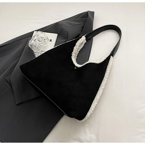 Detailed top view of black suede shoulder bag with white faux fur trim on a blazer