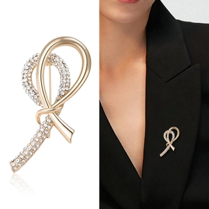 Elegant gold ribbon brooch with rhinestones shown on white background and model sweater