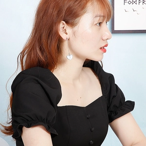 Close-up of long heart drop earrings with white shell texture on model in side view