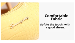 Detail of yellow crocodile embossed leather texture and gold metal logo on shoulder bag