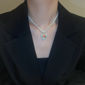 Baroque freshwater pearl necklace with a red rose heart pendant worn by a model