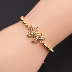 Dettaglio di un bracciale dorato con ciondolo a farfalla in zirconi multicolore vivaci