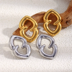 Detail of 18K gold and silver geometric heart earrings on a natural wood background