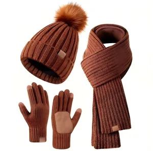 Detailed view of caramel winter knit set including pompom beanie, scarf, and touch gloves