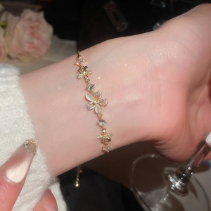 Detail of adjustable gold flower bracelet with opal petals and zircon stones on wrist