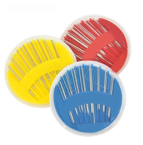 Close-up of household sewing needle set with three colorful round plastic storage cases