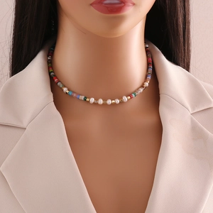Detail view of pearl and colored bead choker necklace on a beige blazer model