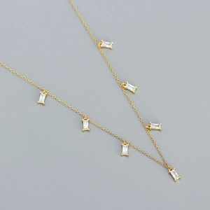 Detail of gold chain necklace featuring several rectangular clear zircon pendants