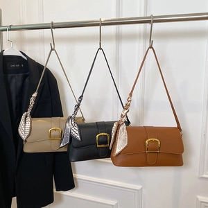 Three leather shoulder bags in beige black and brown with silk scarves on a hanger