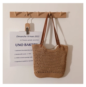 Detail of hollow mesh cotton weave tote bag with brown leather handles on white background