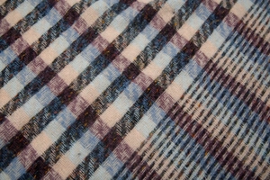 Detailed macro view of soft plaid scarf fabric showing twill weave texture and pastel tones
