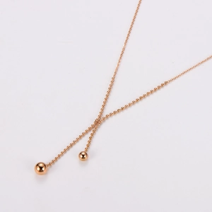 Detail of rose gold double-layer necklace featuring minimalist small bead pendants