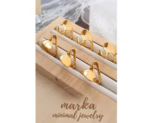 Detailed view of six gold-plated irregular fluid-shaped rings on a velvet display tray