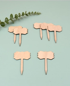 Detailed view of unfinished wooden plant labels with decorative wavy edges on green background