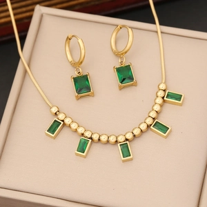 Golden necklace and earring set featuring emerald green rectangular gemstones in a gift box
