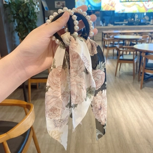 Detail showing floral print silk scarf scrunchie with faux pearl accents in hand