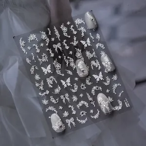 Macro view of white lace flower and butterfly nail stickers with delicate crystal accents