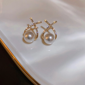 Close-up of geometric gold earrings with sparkling crystals and elegant white pearls
