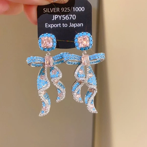 Detail of 925 silver bow earrings featuring turquoise beads and pink zircon crystals
