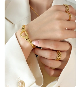 Detail of gold-plated heart chain bracelet and rings set worn by a model