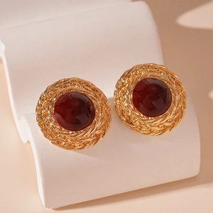Macro view of vintage gold stud earrings with braided texture and burgundy resin center