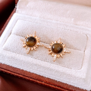 Macro detail of 18K gold plated tiger eye stone stud earrings with starburst zircon accents