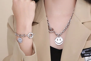 Close-up of stylish stainless steel smiley face necklace and bracelet set with OT clasp