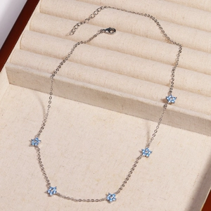 Detail view of silver chain necklace with five blue crystal flowers in a beige display box