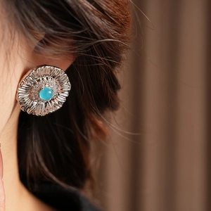 Macro view of vintage silver earrings with green turquoise center and zircon petals